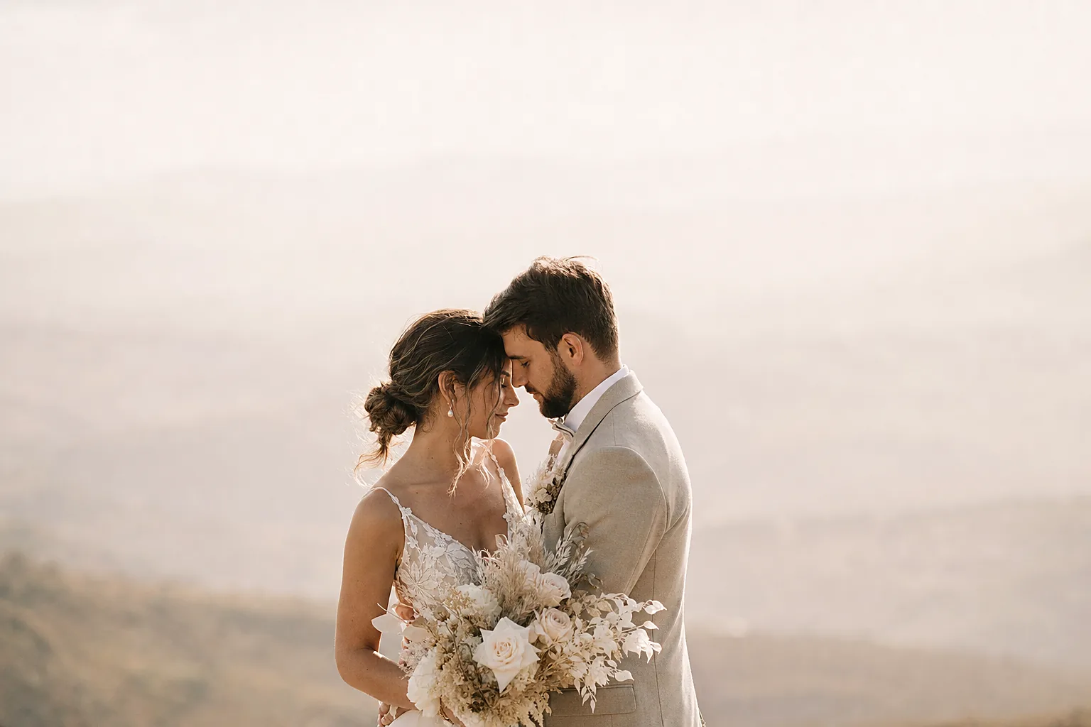 A bride and groom in a tender embrace in soft afternoon light